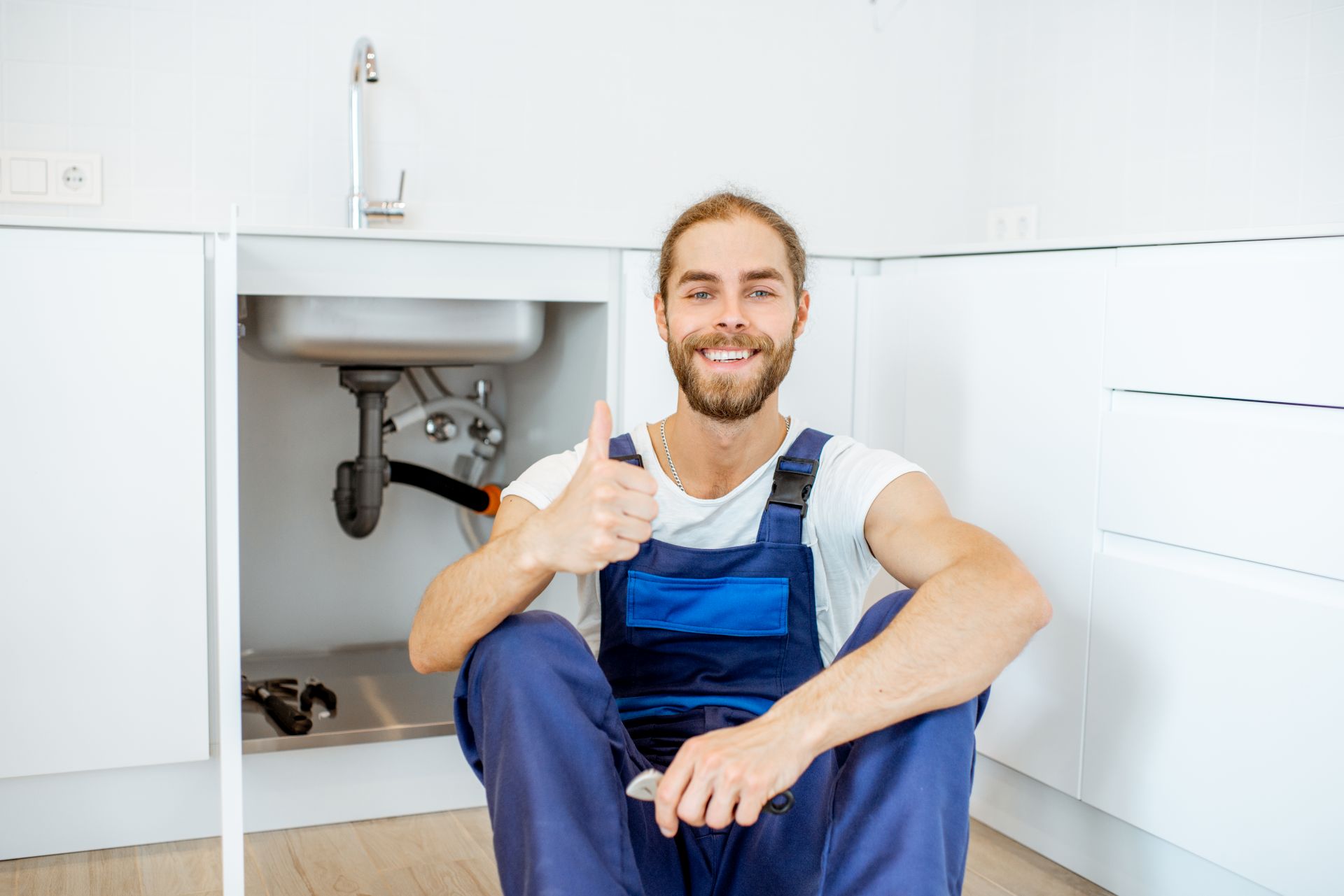 plumber fixing kitchen sink smiling